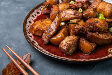 Braised pork belly close-up on a dark background. Chinese food.