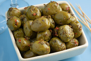 Bowl with Greek green olives and seasoning close up 