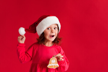 Girl in santa hat with christmas gingerbread bell	