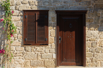 House with brown shutters and door in Antalya Side Village.Seective Focus. Stone Wall and ivy flower.