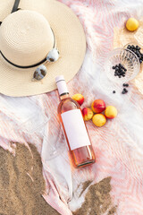 Summer beach picnic on the coast. Bottle of rose wine, fruits, summer accessories. Romantic party concept. Top view - 466442432