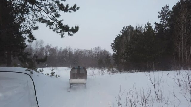 Steadicam shot of snowbikes riding between trees and bushes in siberian forest