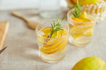 Citrus and rosemary fresh lemonade in glass on a white table at home, summer drink, detox healthy water.