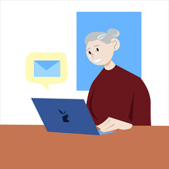 Happy grandmother is sitting at the table with a laptop. Grandma receives a message on her laptop. Grandmother in a red sweater.