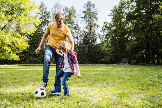 Father and son playing with soccer ball at park