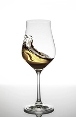 White wine swirling in glass on white background
