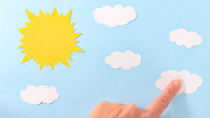 The paper sun and clouds in the paper sky are attached with a finger. Application.