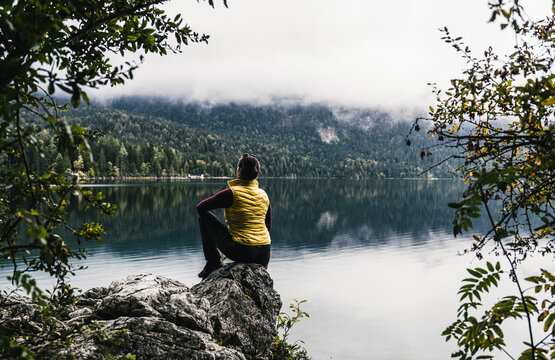 Woman sitting on rock by lake in forest