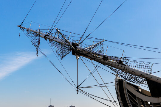 Wooden bowsprit of sailing ship against blue sky.
