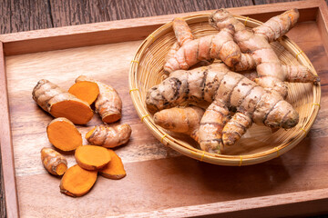 Turmeric root and sliced in wooden plate, Table top view Curcuma Longa Linn or rhizome root on a wooden table background.