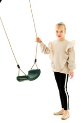 Cute little girl is standing near the swing.