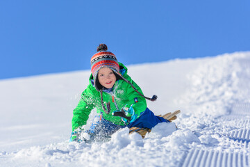 kleiner Junge beim Schlittenfahren im Winter.