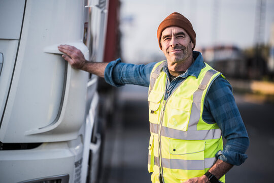 Smiling male driver standing by truck