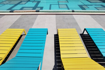 close up view of wooden sun lounger chair by the side of a swimming pool 