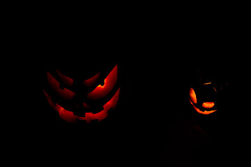 Silly evil orange Halloween pumpkin with his big brother evil smile pumpkin orange fire lit. Scary...