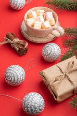 Christmas or New Year composition. Decorations, silver balls, fir and spruce branches, cup of coffee, on a red background. Side view.