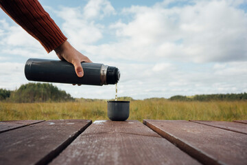 Man pouring tea from insulated bottle in cup