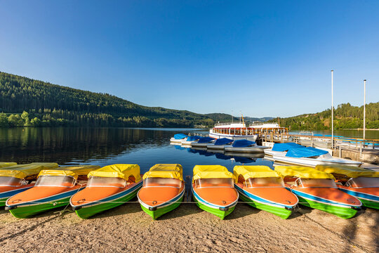 Clear sky over pedal boats left on shore of Titisee lake