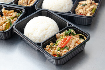 Thai food lunch boxes in plastic packages, Thai Stir Fried Pork with Basil and Rice (Pad Ka Prao).
