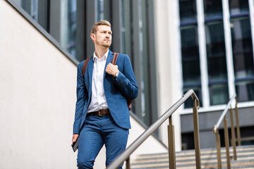 Male professional with backpack walking down on steps