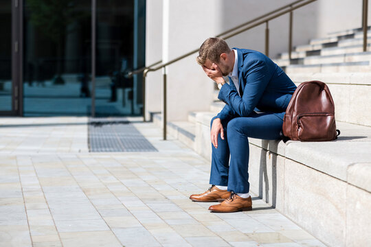 Worried businessman with head in hand sitting on steps