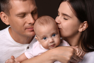 Happy family with little baby on dark background