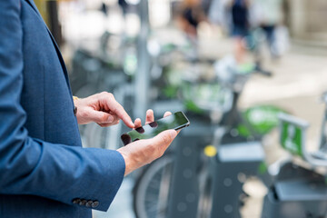 Young male professional using smart phone at bicycle parking station