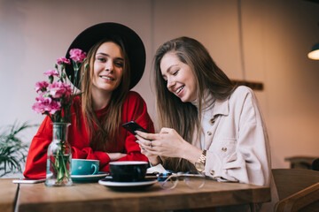 Joyful friends spending time together in cozy cafe