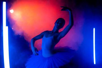 Graceful ballerina in tutu dress dancing with hands, color neon light with smoke. Woman with long dark nails and airy skirt. Studio shot. Art concept.