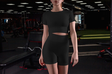 Obraz na płótnie Canvas Mockup of a black compression suit, cropped t-shirt, shorts on a sporty girl on the background in the gym.