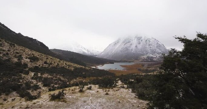 Aerial drone shot during hail storm featuring streams, river and snowy mountain range over Lake Selfe