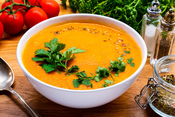 Cream tomato soup with fresh parsley on wooden table
