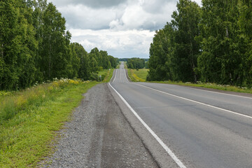 Asphalt lonely road between trees. Road in Russia. Kemerovo region