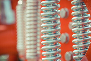 Big and hard steel silver spring as part and detail of red industrial or agricultural machine