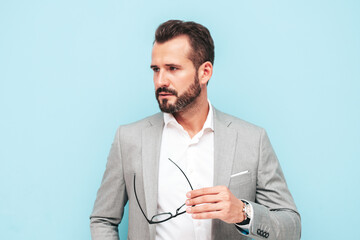 Closeup portrait of handsome confident stylish hipster lambersexual model.Sexy modern man dressed in elegant suit. Fashion male posing in studio near blue wall