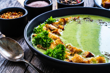 Cream zucchini soup with croutons and fresh parsley on wooden table
