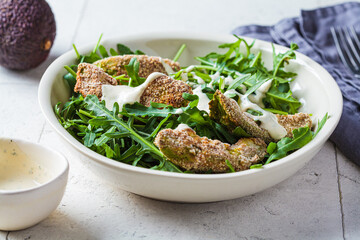 Batter-fried avocado with arugula and tahini dressing. Vegan food concept.