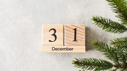 Wooden bars show date of New Year eve on white background with Christmas tree branch