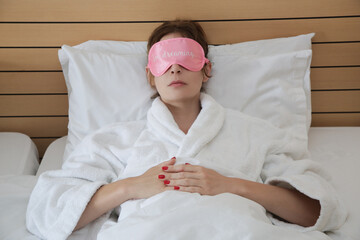 Young beautiful woman wearing pink sleep mask and resting in bed.
