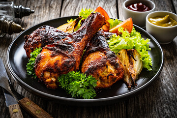 Barbecue chicken drumsticks with fresh vegetables on wooden table
