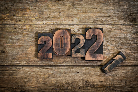 Change from year 2021 to 2022 set with vintage letterpress printing block numbers on rustic wood background