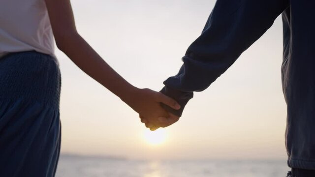 Close up of LGBT Asian couple holding hands together on beach in summer