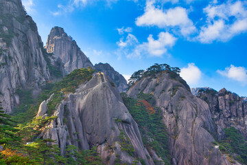 High granite mountains with green trees, blue sky and white clouds. Landscape of Mount Huangshan (Yellow Mountain). UNESCO World Heritage Site. Anhui Province, China.