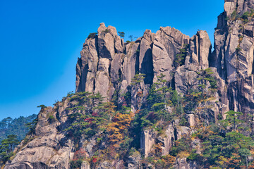 High granite mountains with green trees, blue sky and white clouds. Landscape of Mount Huangshan (Yellow Mountain). UNESCO World Heritage Site. Anhui Province, China.