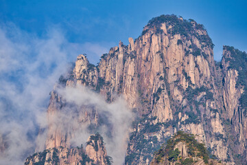 A dynamic view of white clouds surrounding a granite mountain. Landscape of Mount Huangshan (Yellow Mountain). UNESCO World Heritage Site. Anhui Province, China.