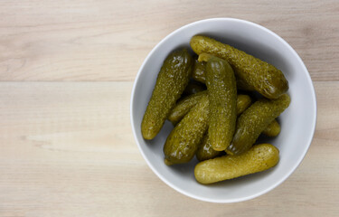 Pickled cucumbers in a bowl top view frame stock images. Marinated gherkins in a white bowl on a wooden background with copy space for text stock photo