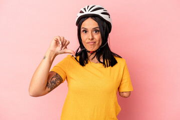 Young caucasian woman with one arm wearing a bike helmet isolated on pink background showing a dislike gesture, thumbs down. Disagreement concept.