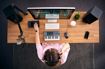 Overhead View Of Female Musician At Workstation With Keyboard And Microphone In Studio