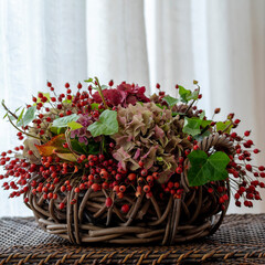 Autumn flower arrangement in basket, window background