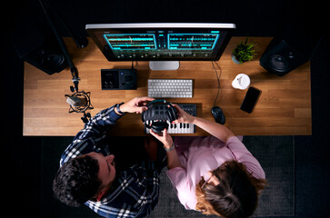 Overhead View Of Male And Female Musicians At Workstation With Keyboard And Microphone In Studio